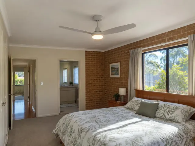 Bedroom ceiling fan in a brick-walled home interior with window and bed in Davidson
