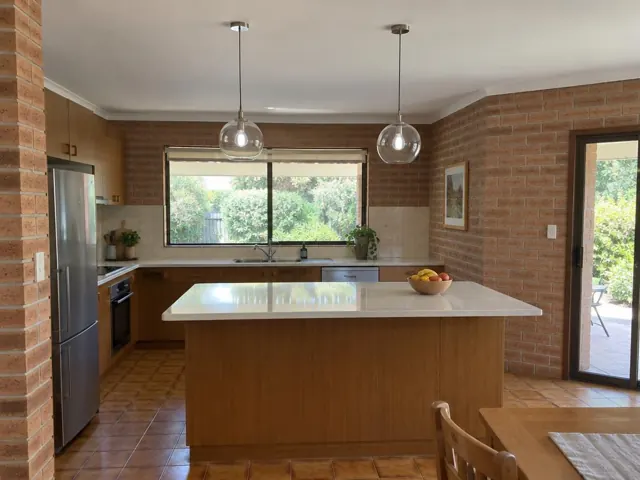 Kitchen with two glass pendant lights above a central island in a brick home interior in Davidson